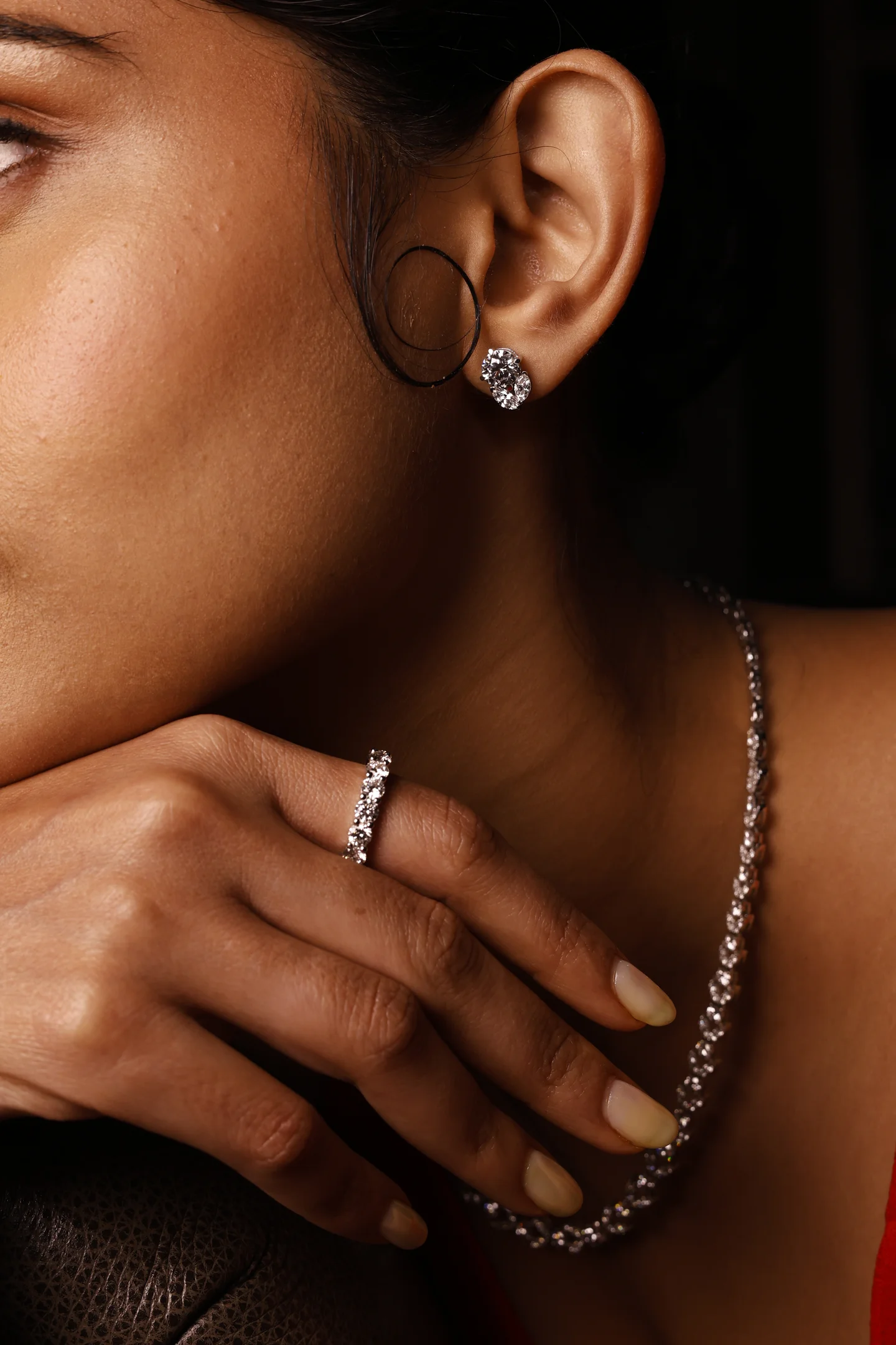 A close-up of Aurique stud earrings, a ring and necklace worn together.
