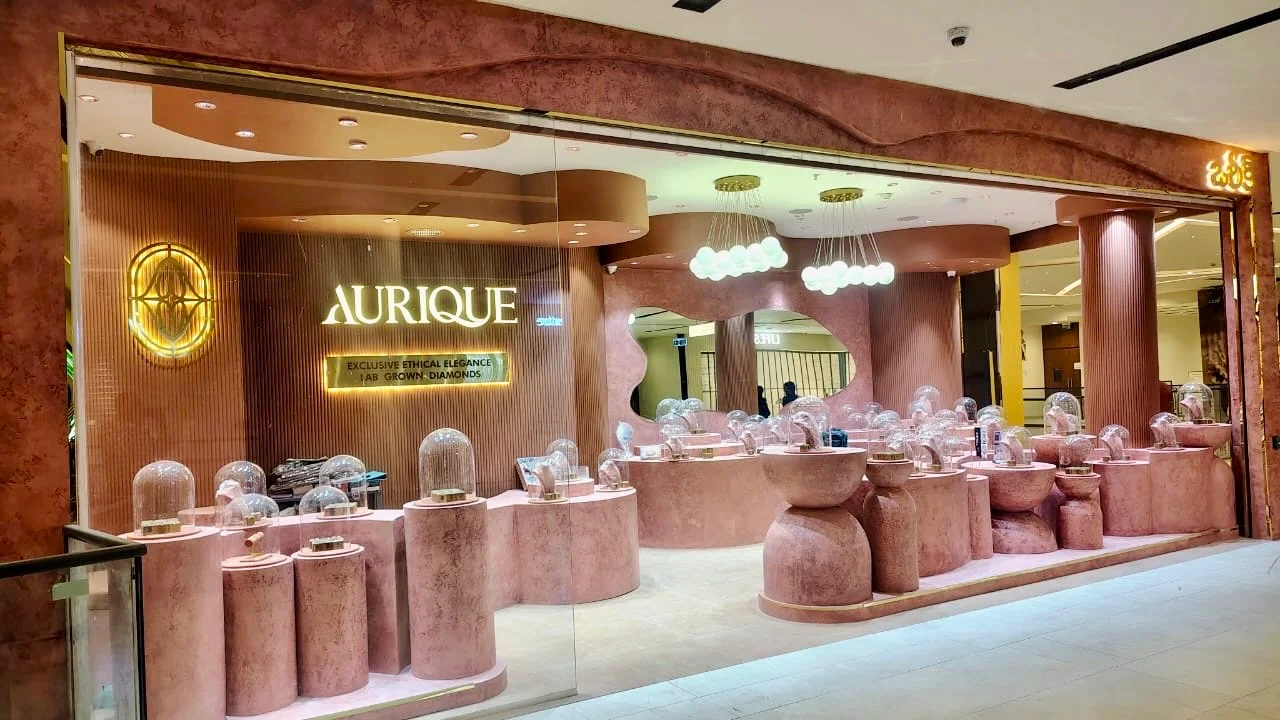 Wide Aurique glass storefront with curved display plinths and warm pendant lighting